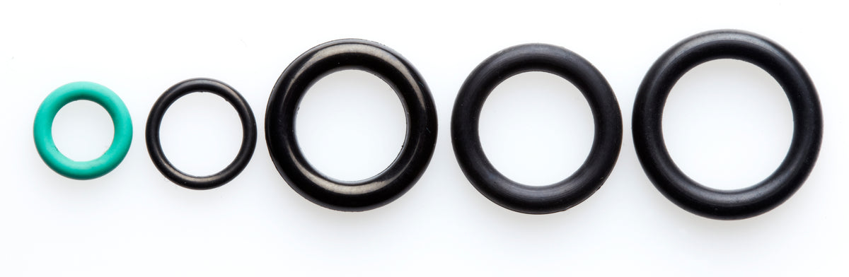 Five O-rings of varying sizes and colors, including one green, arranged in a row on a white background, showcasing replacement parts for high-pressure cleaners.
