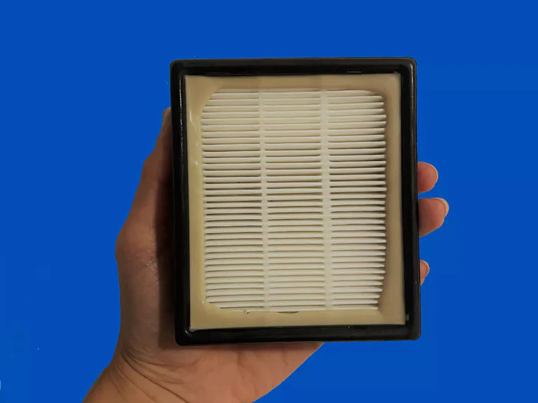 Hand holding a clean HEPA filter against a vibrant blue background, showcasing its fine pleated design for air purification.