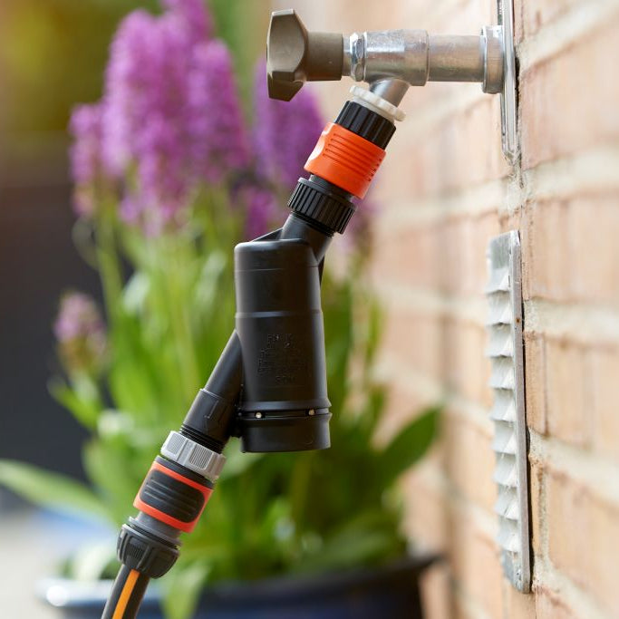 High-pressure cleaner valve for pressure washers by ES, attached to a brick wall with a metal vent.