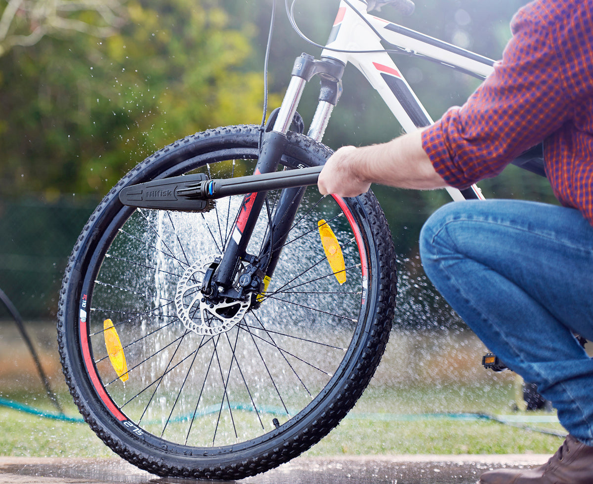 High-pressure cleaner accessory kit for cars by Nilfisk with bicycle being cleaned.