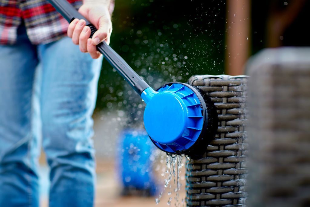 Rotary brush high-pressure cleaner accessory for high-pressure cleaners, cleaning a wicker furniture with running water.
