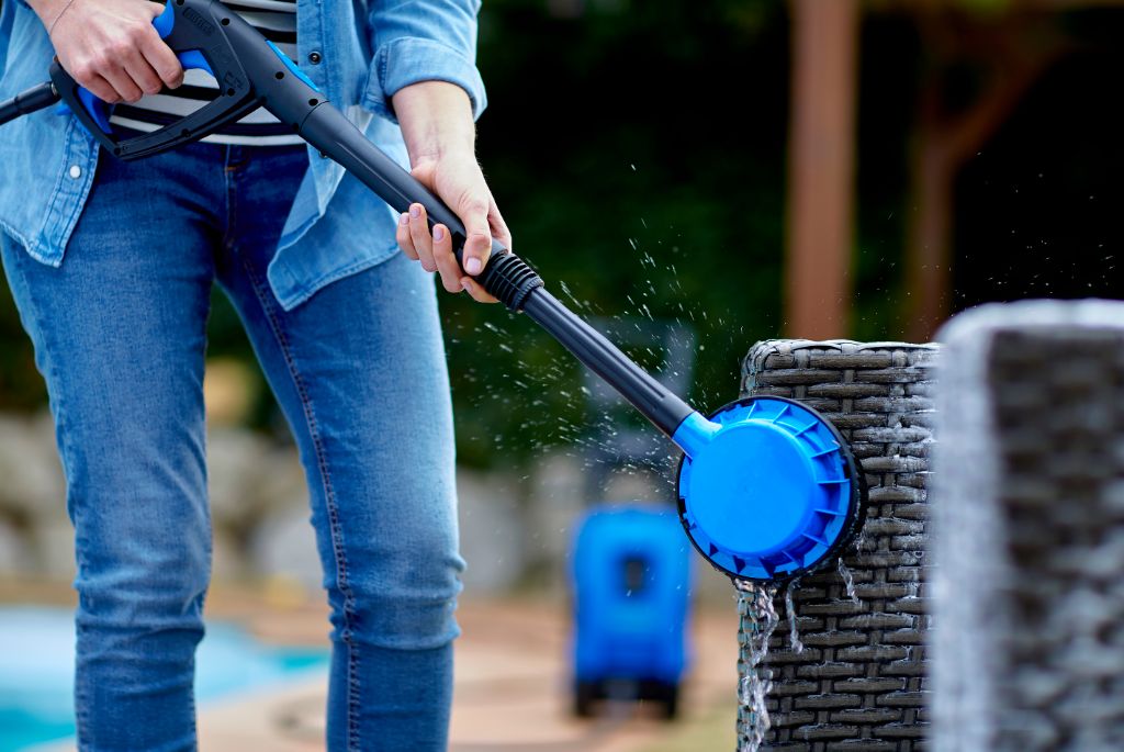 Rotating brush accessory for pressure washers, alongside denim-clad person cleaning furniture.
