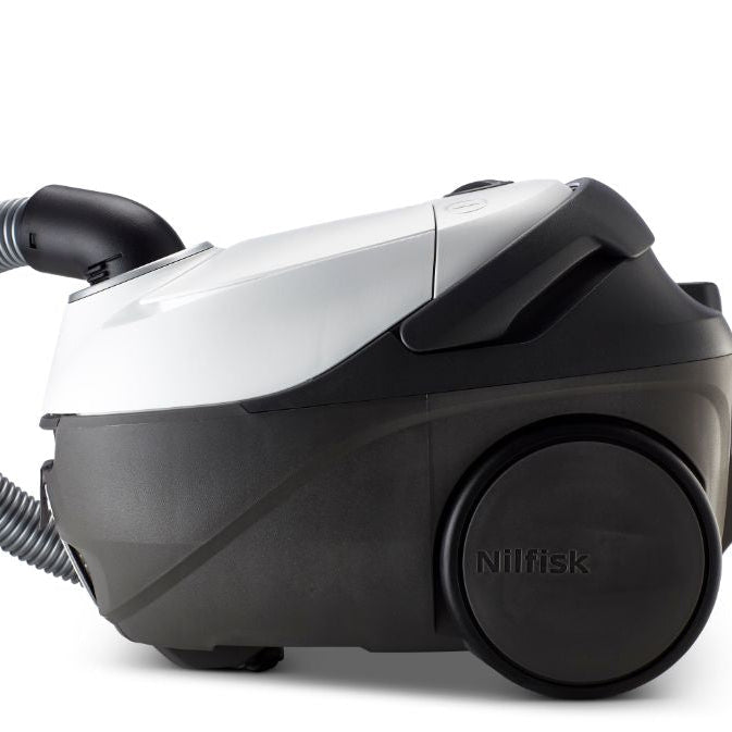 White and black canister vacuum cleaner by Nilfisk with gray flexible hose and large rear wheel, side view on white background