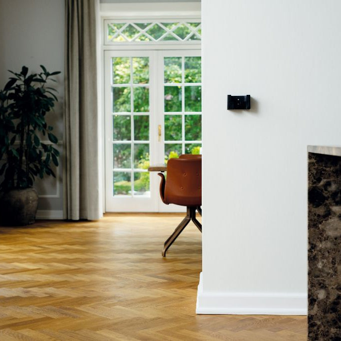 Vacuum cleaner accessory wall mount from S1 støvsugere on white wall with herringbone floor.