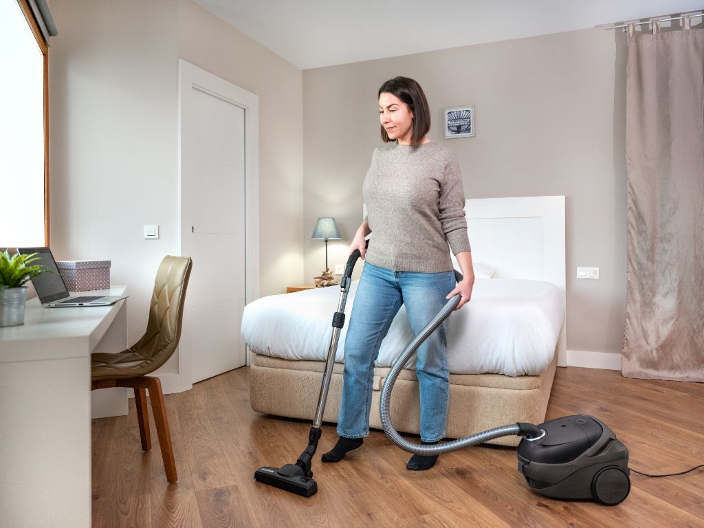 Black ES One vacuum cleaner at use, with a woman wearing jeans and a grey sweater.