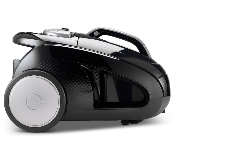Black canister vacuum by Meteor, featuring silver accents and a round wheel, displayed in a side view.
