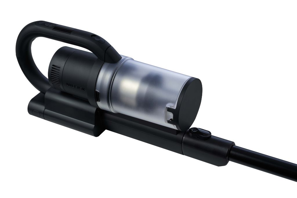 Cordless stick vacuum cleaner, by Nilfisk, shown at an angle and with a clear collection cylinder.