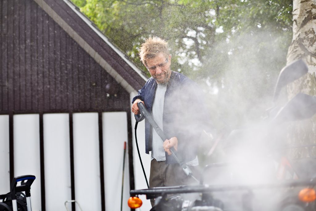 Pressure washer by ES Premium being used by a man with water spraying around it.
