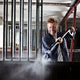 High pressure washer by Premium being used for cleaning an enclosure, featuring a man wearing safety glasses.