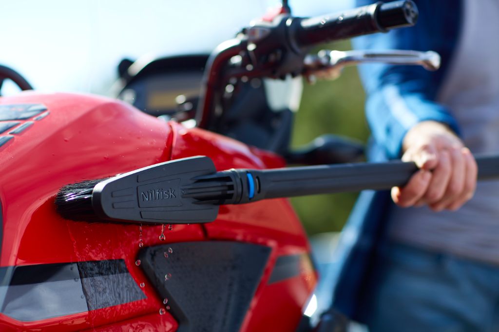 High-pressure cleaner accessories kit by Nilfisk on a red motorcycle.