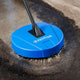 Blue pressure washer brush by Nilfisk cleaning dirty concrete surface with a dark handle.
