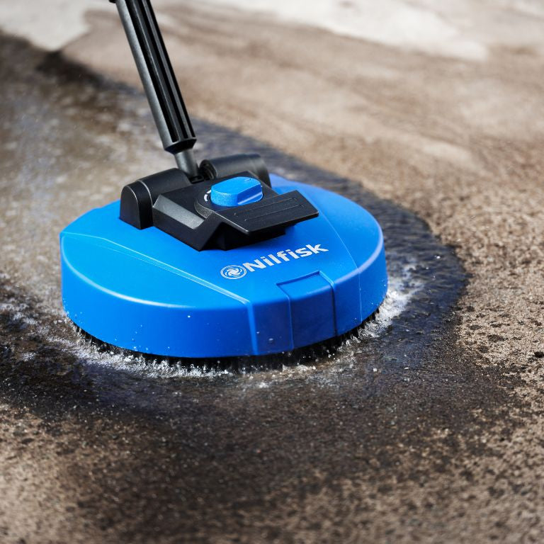 Blue patio cleaner by Nilfisk, attached to a black handle and cleaning a stained surface.