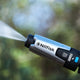 High-pressure washer by Nilfisk featuring a silver nozzle, along with a blue gentle mode button, and a water stream.
