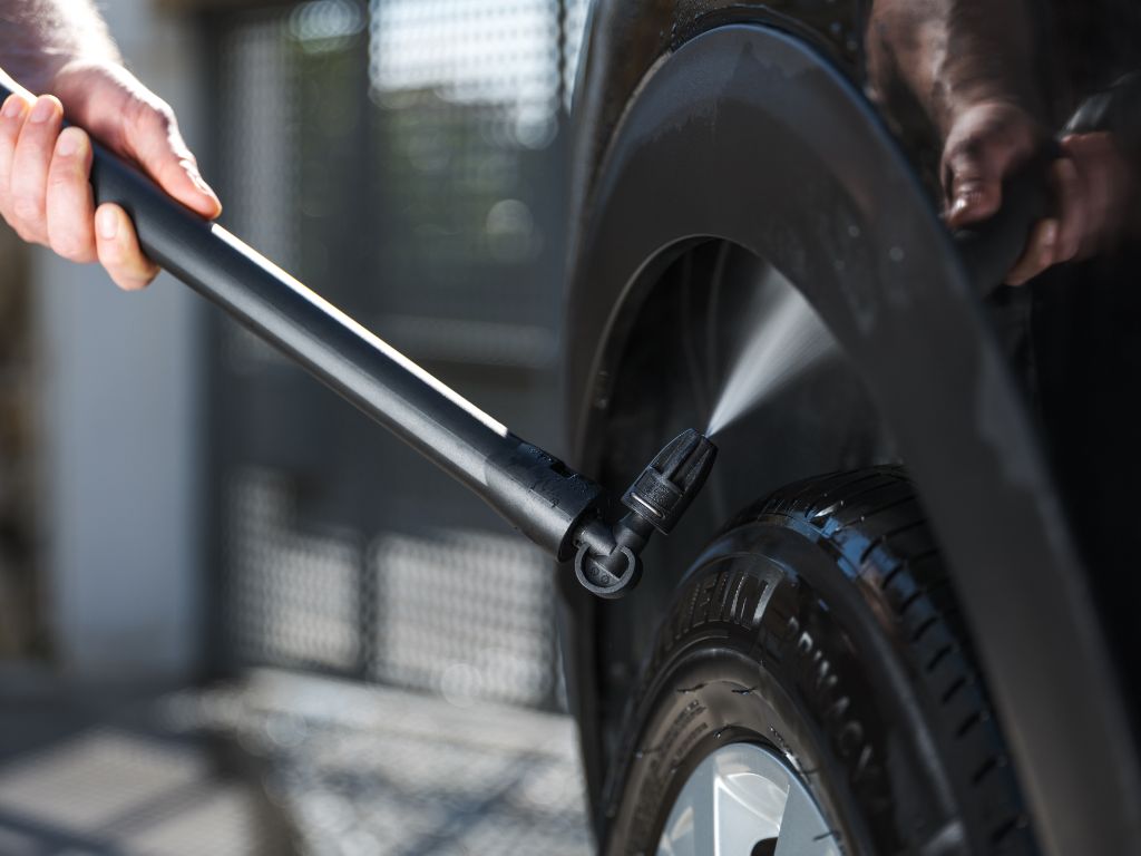 High-pressure washer attachment by ES, cleaning the tire of a car with water.