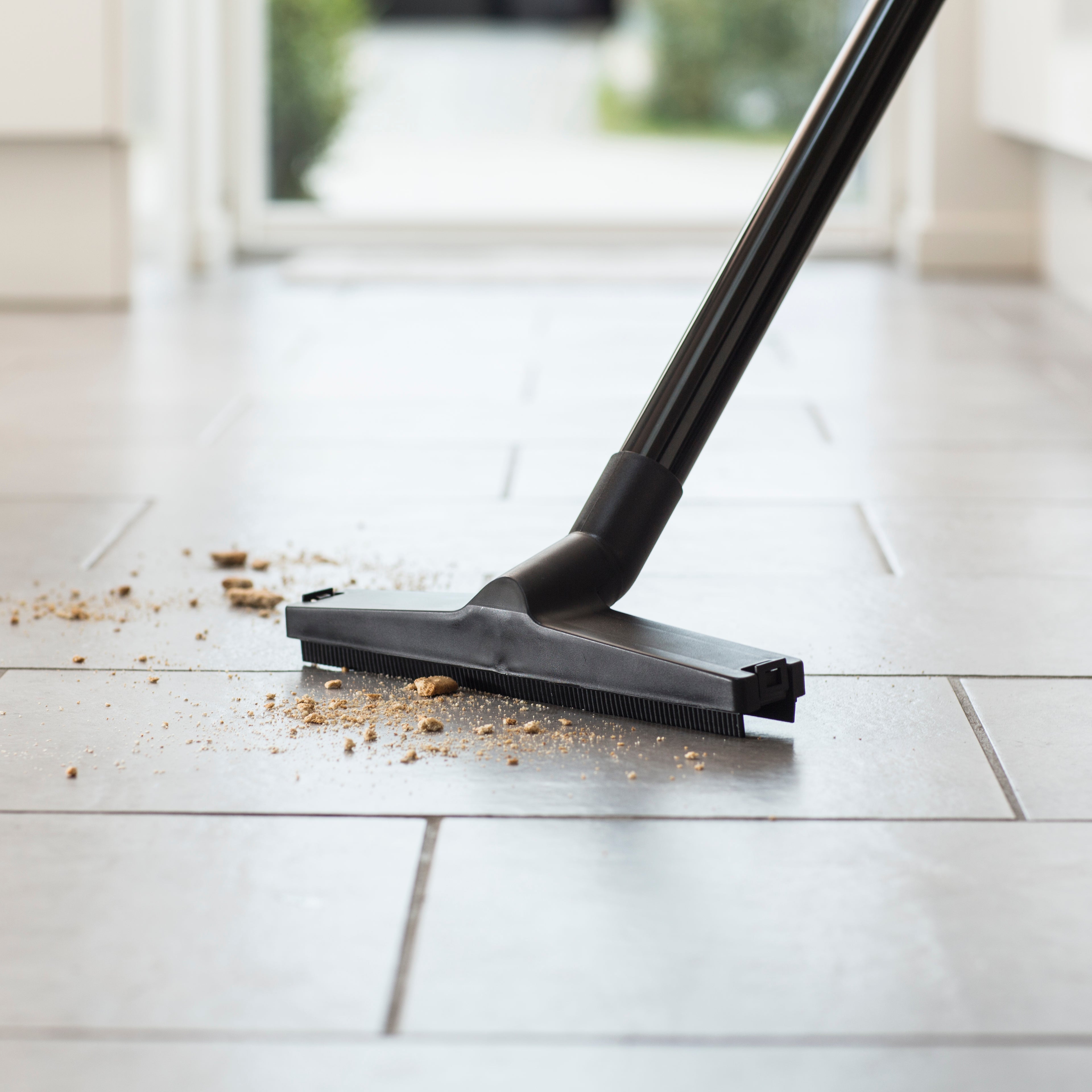 Wet/dry vacuum cleaner, 12 car by ES Buddy II, cleaning crumbs off a tiled floor.