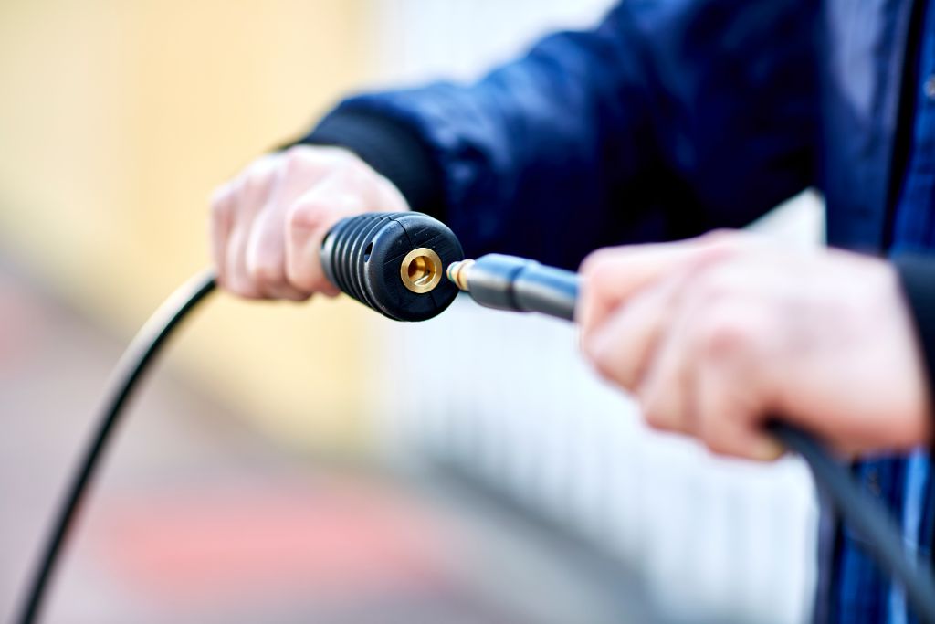 Black pressure washer hose with brass fitting, being connected to another hose.