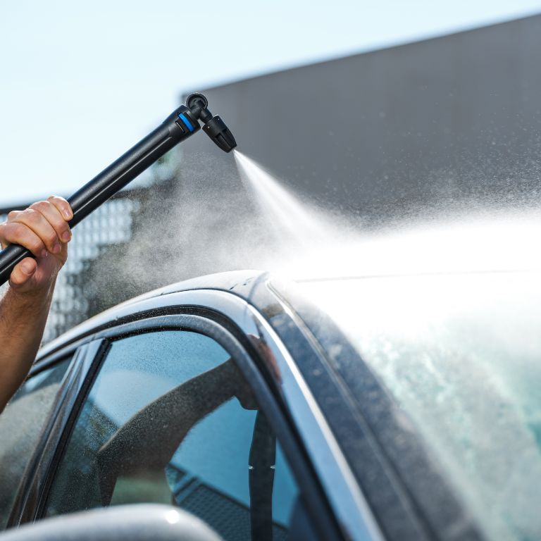 Pressure washer undercarriage nozzle for high-pressure cleaners with a black wand spraying water onto a car.