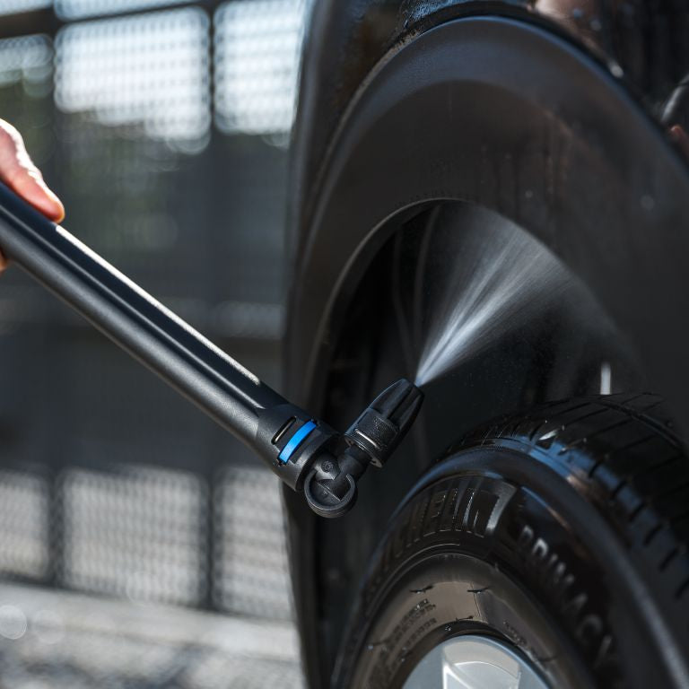 Undercarriage nozzle for pressure washers by ES, cleaning a car tire with a jet of water.