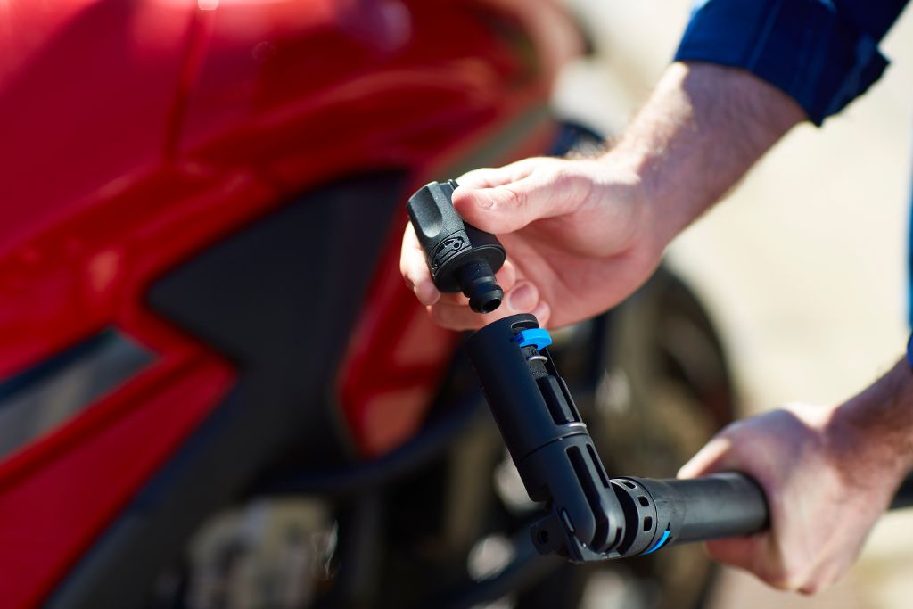 High-pressure washer accessory adapter for high-pressure cleaners, near a red motorbike.