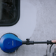 Blue rotating brush for pressure washers by Nilfisk, cleaning a vehicle.
