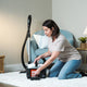 White vacuum cleaner, 650 W, with an orange filter being removed, near a blue armchair and wicker basket.