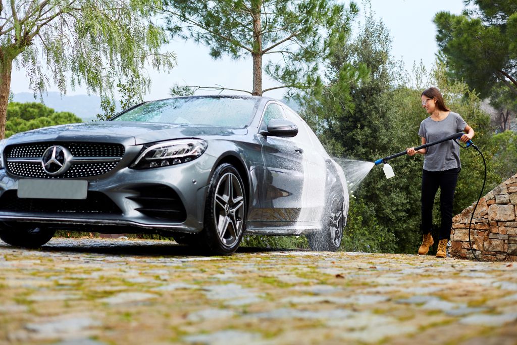High-pressure washer accessory kit for car washing from ES, attached to a nozzle and spraying a grey car.