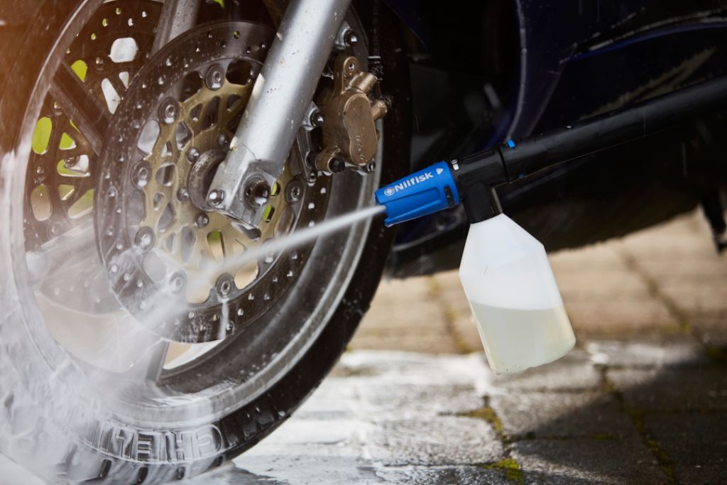 Bike and motorcycle cleaner fluid by Nilfisk, applied to a motorcycle wheel with a pressure washer.