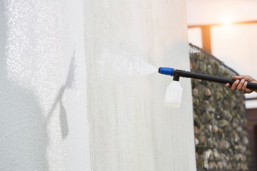 High-pressure cleaner detergent by ES Active, used on a cement wall for cleaning.
