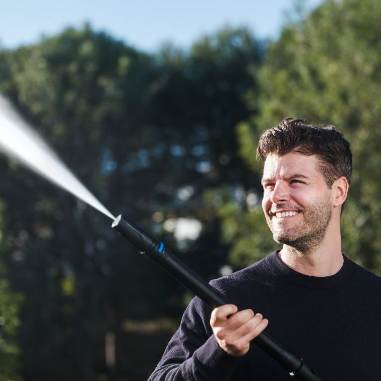 High-pressure cleaner by ES with a black hose being used outdoors.