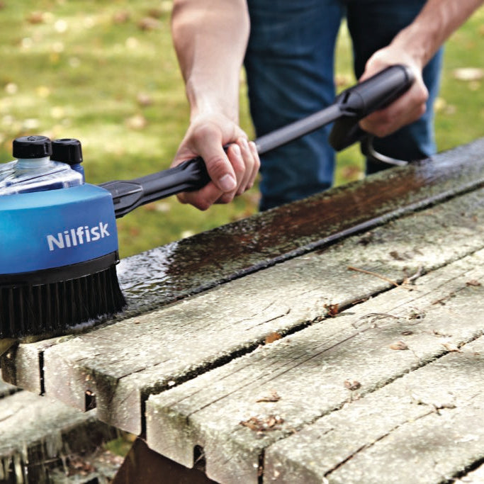 Blue multi brush for pressure washers by Nilfisk cleaning a wooden picnic table.