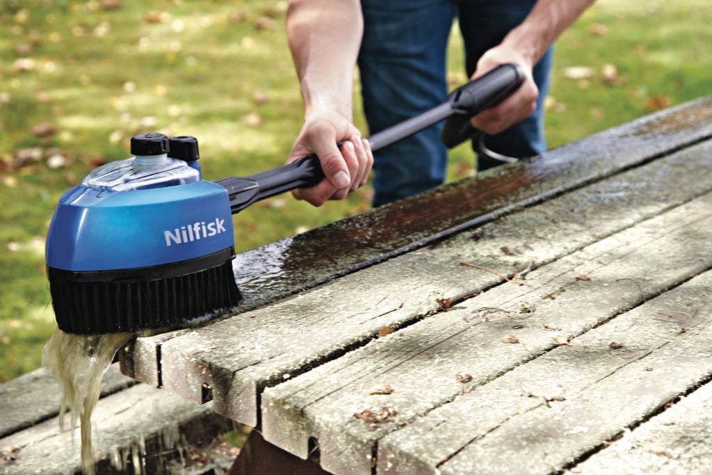 Blue multi brush for pressure washers by Nilfisk cleaning a wooden picnic table.