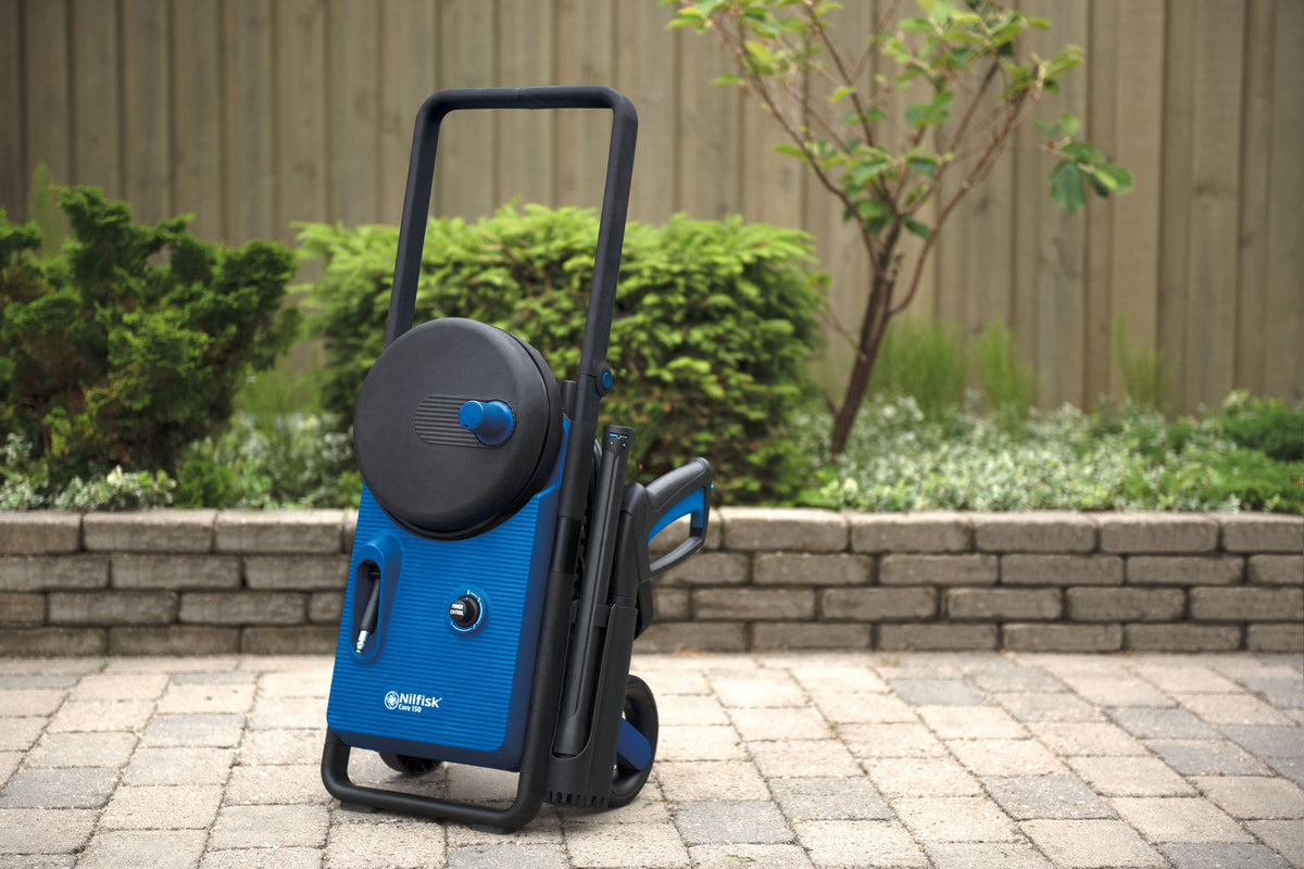 Blue pressure washer by Nilfisk with black accents, displayed outdoors on a brick-paved surface.