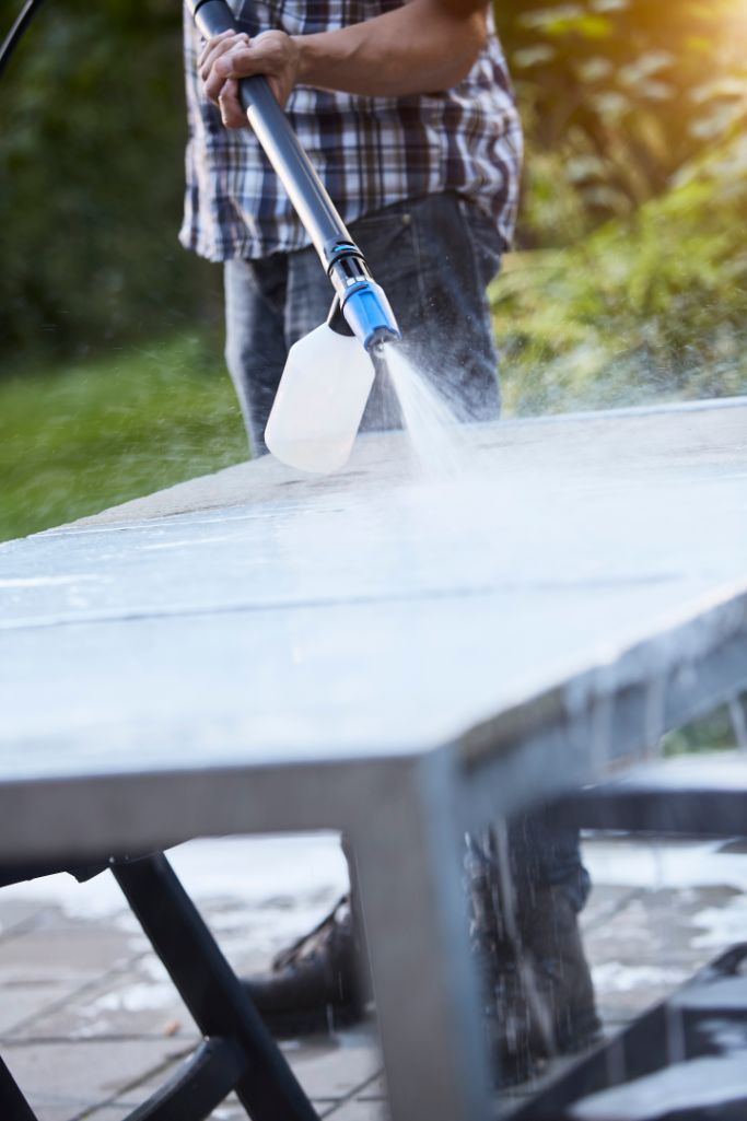 Stone sealer by ES being sprayed onto stone surface, with visible plaid shirt and jeans.