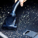 Black wet/dry vacuum by ES Buddy II cleaning up dirt from the floor.
