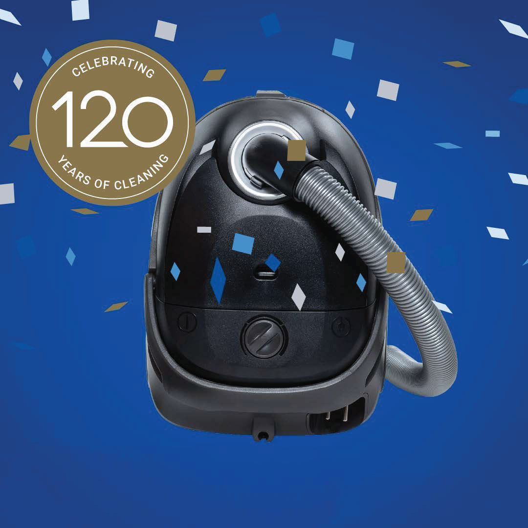 Black canister vacuum cleaner by One R, 750 W, with silver hose and 120-year anniversary badge on blue confetti background