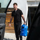 Blue wet and dry vacuum cleaner by Nilfisk, carried by a man in a black polo shirt with a white building in the background.
