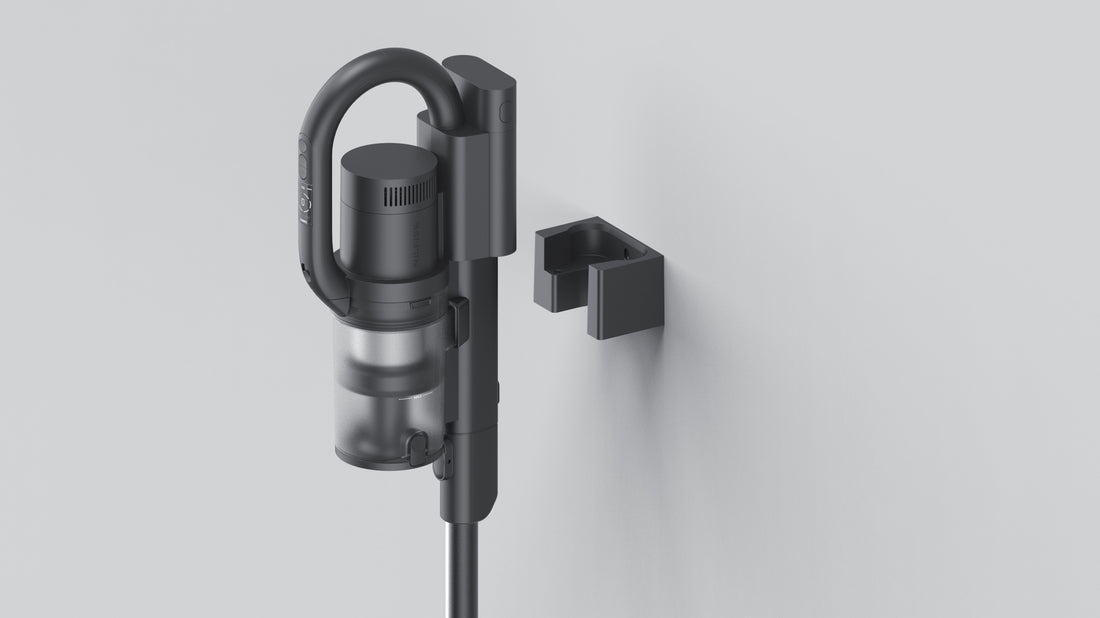 Dark gray cordless stick vacuum with transparent dustbin mounted on wall dock, minimalist design, soft lighting.