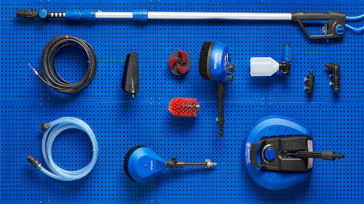Blue pegboard displays Nitek pressure washing tools, hoses, brushes, and accessories arranged neatly.
