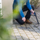 High-pressure cleaner accessory by ES, cleaning a sewer drain on a cobblestone patio.