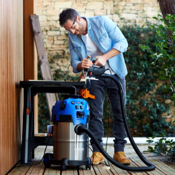 Wet and dry vacuum cleaner with floor nozzle by Nilfisk, next to a carpenter cutting wood.