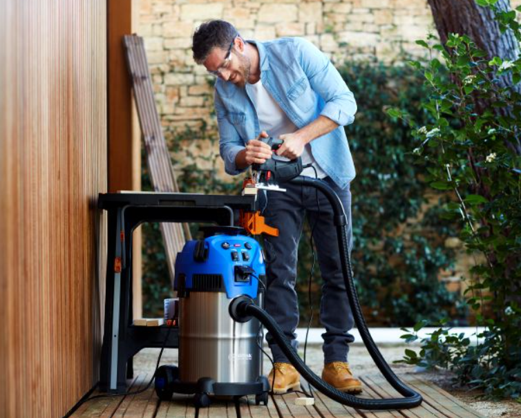 Wet and dry vacuum cleaner with floor nozzle by Nilfisk, next to a carpenter cutting wood.
