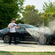High-pressure washer spray handle from ES, being used to clean a black car.